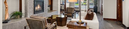 A modern lobby with a fireplace, sofa, chairs, and a television.
