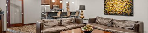 A living room with a brown couch and a painting on the wall.