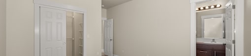 A large room with carpeted flooring, a closet, and an adjacent bathroom.