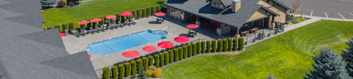 Overhead view of a large swimming pool behind a building surrounded by a neighborhood.