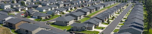 A large housing development with rows of houses and mountains in the distance.