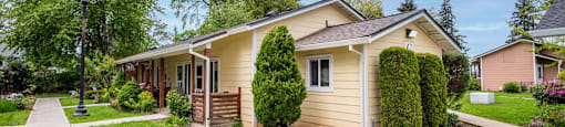 a small yellow house with a sidewalk in front of it