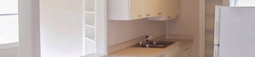 an empty kitchen with wooden floors and white walls