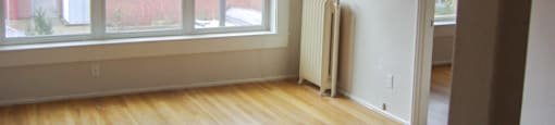 an empty living room with wooden floors and white walls