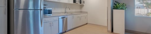 A kitchen with a stainless steel refrigerator and white cabinets.