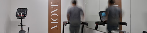 A gym with a treadmill, a bench and a dumbbell rack.