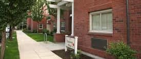A white sign is in front of a red brick building.