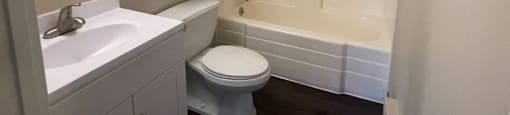 A white bathroom with a toilet, sink, and bathtub.