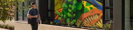 a man walking in front of a building with a mural of a bird