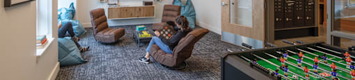 a living room with a foosball table and two people sitting in chairs