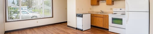 an empty kitchen with white appliances and wood floors