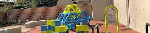 A playground with a yellow slide and blue and green blocks.