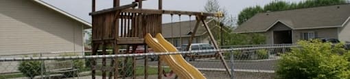 a playground with a wooden playset and a slide