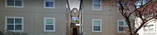 two buildings and a passage way between them with a tree in front on the right side
