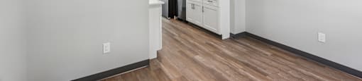 A kitchen with white cabinets and a wooden floor.