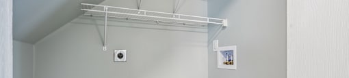 A white wall with a shelf and a small picture on it.