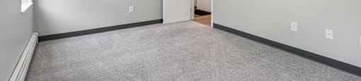 A room with a carpeted floor and a door on the right side.
