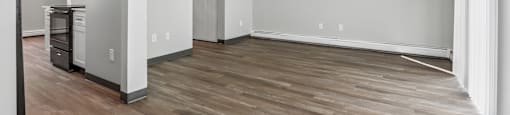 A spacious room with wooden flooring and white walls.