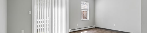 A room with wooden flooring and a window with blinds.