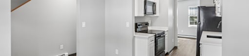 A kitchen with white appliances and wood floors.