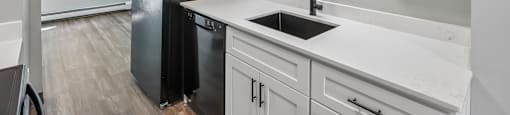 A kitchen with black and white cabinets and a black fridge.