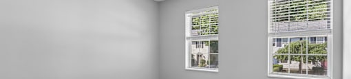 A room with a grey wall and a window with blinds.