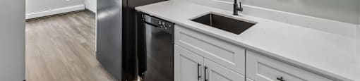 A kitchen with white cabinets and a black fridge.