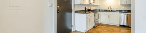 a kitchen with white cabinetry and black countertops