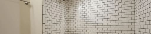 a bathroom with white tiles and a white bathtub