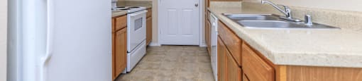 an empty kitchen with a white refrigerator and a sink