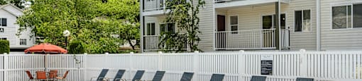 a swimming pool with chairs in front of a house at Sage Apartments, Washington