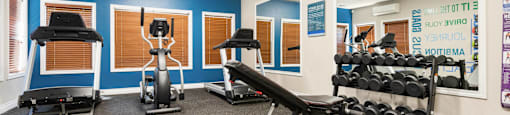 a gym with weights and exercise equipment in a room with blue walls at Sage Apartments, Everett, Washington