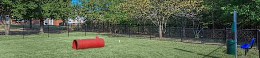 a dog park with a red cylinder in the grass at Villas of Sorrento Apartments, Dallas, Texas