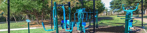 a playground with blue equipment in a park at Villas of Sorrento Apartments, Dallas, TX