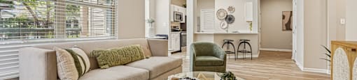 A living room with a beige couch, a green chair, and a coffee table.