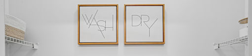 Two dryers are in a laundry room with dry and wash signs on the wall.