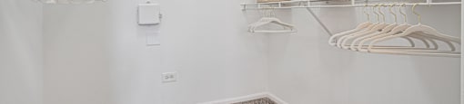 A white closet with clothes hanging and shelves with baskets.