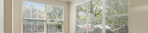 A room with a window covered by white blinds.