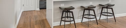 A kitchen with a white counter top and bar stools.
