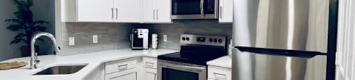 kitchen with stainless steel appliances and white cabinets at Mainstreet Apartments, Florida
