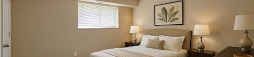 A bedroom with a bed, nightstands, and lamps.