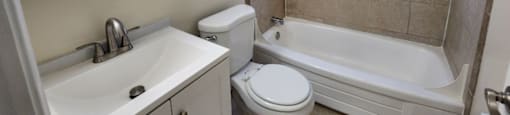 A white sink and toilet in a bathroom with a white bathtub.
