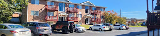 Cars parked in front of a multi-story apartment building.
