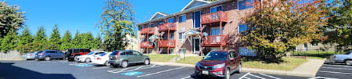 A parking lot with cars and a red building in the background.