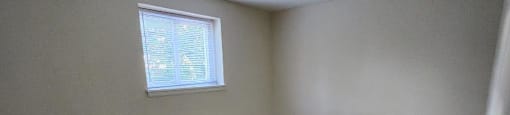 A room with a carpeted floor and a small window.