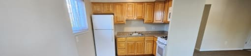 A kitchen with white appliances and wooden cabinets.