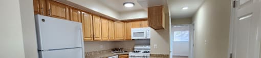 A kitchen with white appliances and wooden cabinets.