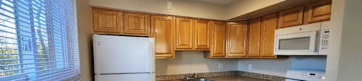 A kitchen with white appliances and wooden cabinets.
