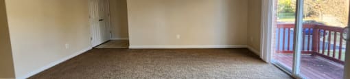 A room with carpeted floor and a door leading to a balcony.