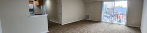 A spacious room with a carpeted floor and a staircase leading to another room.